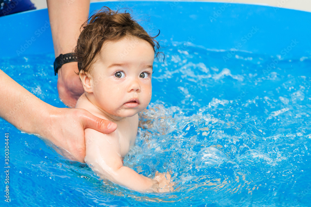 Happy baby learning to swim, swim with fun in the pool to keep fit. baby enjoys his first swim in the pool infant swimming in the children's pool. Water park. Summer holiday. Happy baby learning to swim, swim with fun in the pool to keep fit. baby enjoys his first swim in the pool infant swimming in the children's pool. Water park. Summer holiday.