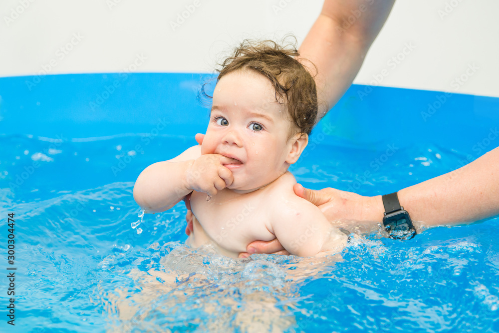 Happy baby learning to swim, swim with fun in the pool to keep fit. baby enjoys his first swim in the pool infant swimming in the children's pool. Water park. Summer holiday. Happy baby learning to swim, swim with fun in the pool to keep fit. baby enjoys his first swim in the pool infant swimming in the children's pool. Water park. Summer holiday.