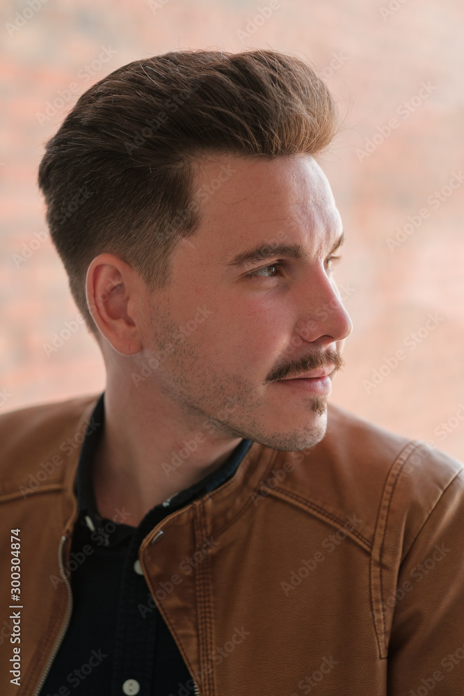 Fototapeta premium portrait of a young guy in a black shirt and brown leather jacket. casual style