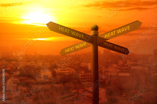 Signpost with a heatwave text direction on the city with the glowing sun background photo