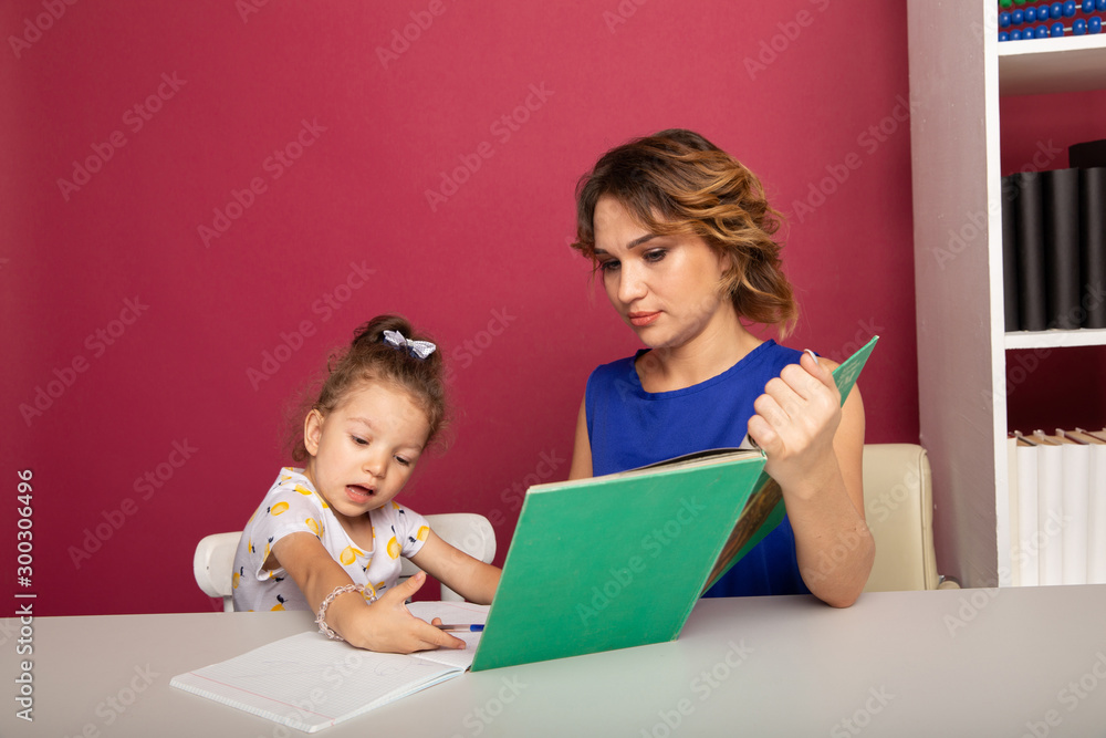 Pretty mother with cute daughter sitting with book in the room at home Pretty mother with cute daughter sitting with book in the room at home