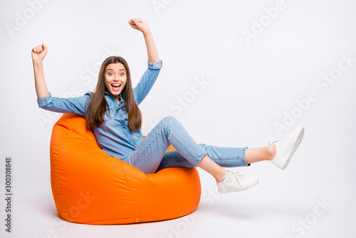 Full length photo of amazed crazy girl sit bag chair watch sport competition victory impressed scream wow omg raise fists wear casual style outfit isolated over white color background