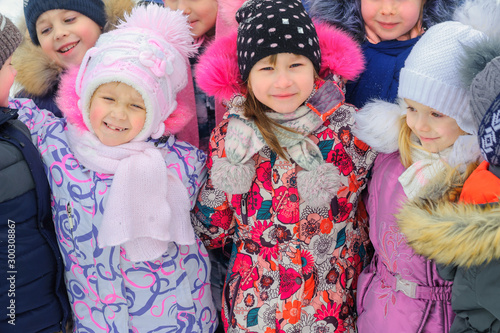 A group of children are playing and having fun on a winter playground. Friends are hugging and smiling. Winter fun. holidays