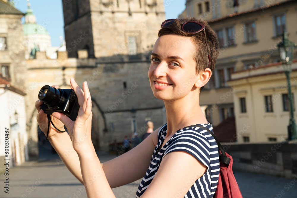 Young woman takes pictures on a walk around the old city on a tourist trip. Prague, Charles Bridge.