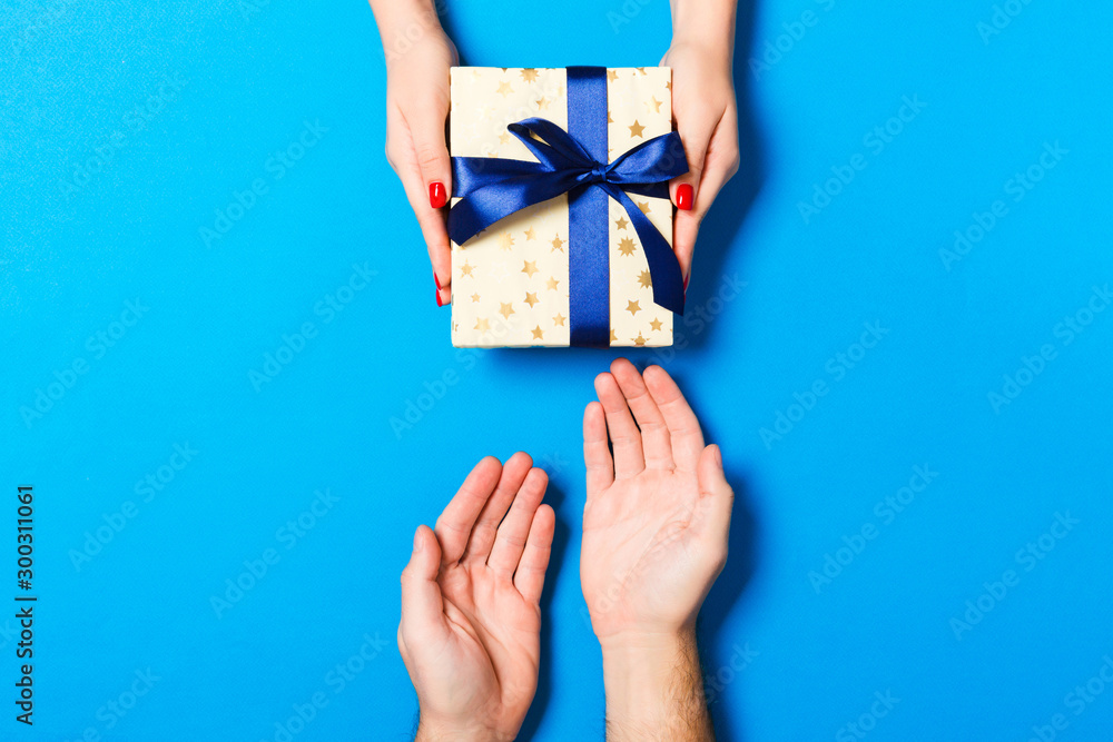 Top view of a gift in male and female hands on colorful background. Congratulation of each other concept. Close up Top view of a gift in male and female hands on colorful background. Congratulation of each other concept. Close up