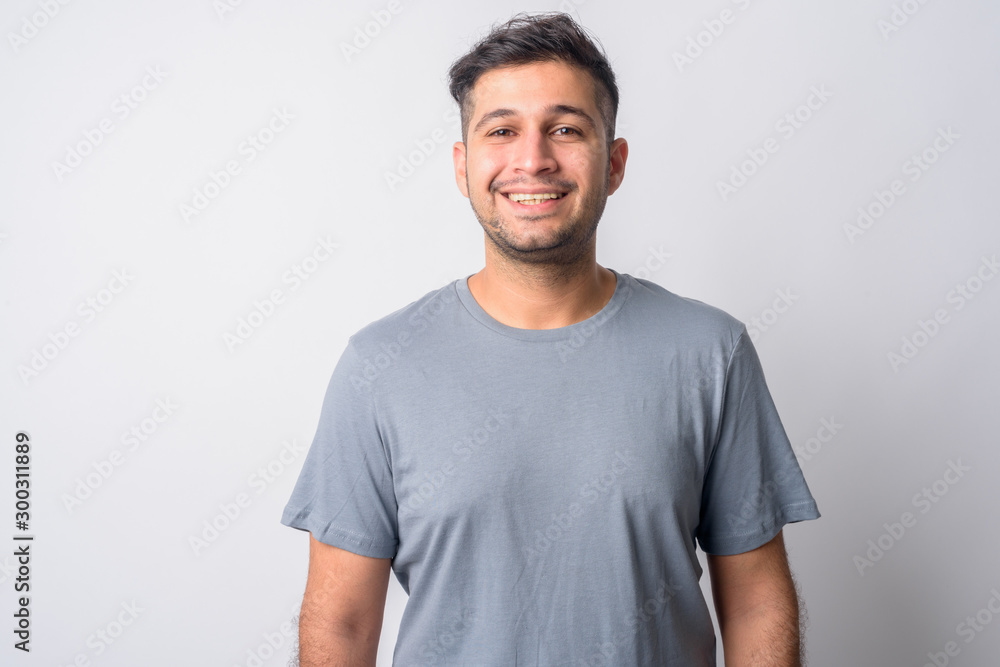Portrait of happy young handsome Persian man smiling - obrazy, fototapety, plakaty 