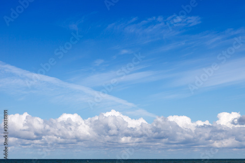 Beautiful blue sky over the sea with translucent, white, Cirrus and Cumulus clouds. Skyline