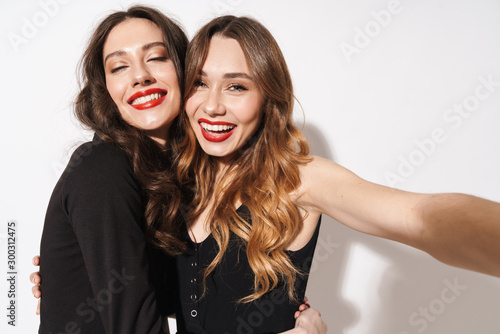 Portrait of two smiling women taking selfie photo and hugging