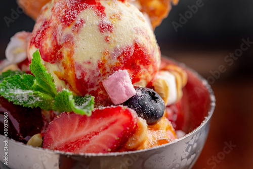 Strawberry ice cream balls with marshmallows, mint, berries and waffles in an iron bowl photo