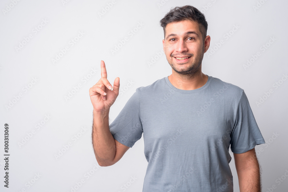 Portrait of happy young handsome Persian man pointing up Portrait of happy young handsome Persian man pointing up