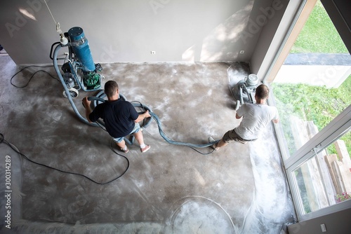 Construction worker in a family home living room that grind the concrete surface before applying epoxy flooring.Polyurethane and epoxy flooring.Concrete grinding. photo