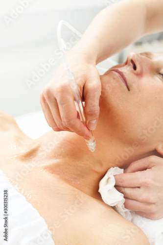 Oxygen oxybrasion. Smooth neck and cleavage The beautician performs oxygen oxybrasion treatment on the skin of the neckline and neck of a woman. Care treatment  skin cleansing