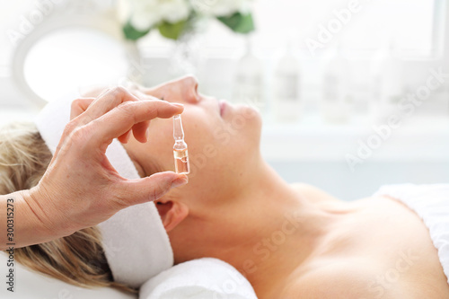 Professional care in a beauty salon. The beautician applies a cosmetic preparation in an ampoule photo
