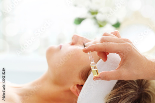 Care treatment in a beauty salon. The beautician applies a cosmetic preparation in an ampoule