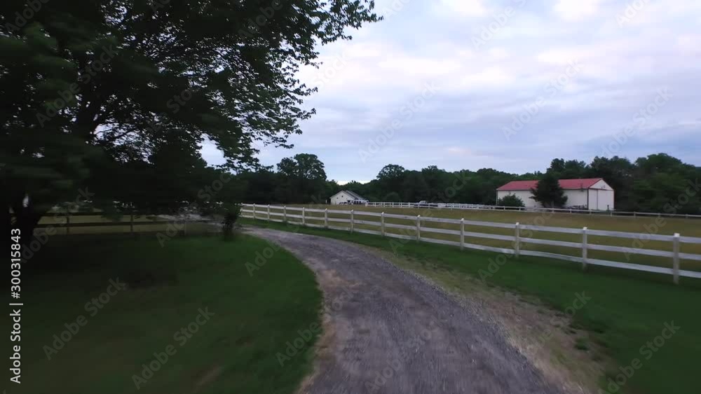 Drone flying down farm road between white Pickett fences rising to reveal house and yard 4K Drone flying down farm road between white Pickett fences rising to reveal house and yard 4K