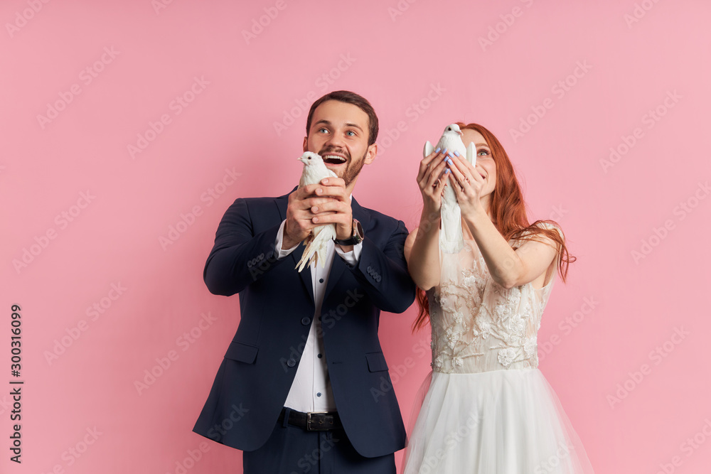 Charming lady and bearded caucasian man in tuxedo let pigeon out of hands, symbol of happy family life. Love, couple, relationships concept Charming lady and bearded caucasian man in tuxedo let pigeon out of hands, symbol of happy family life. Love, couple, relationships concept