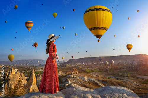 Beautiful girl standing and looking to hot air balloons in Cappadocia, Turkey.