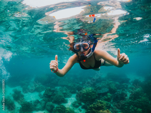 Young woman snorkeling on tropical beach. Underwater sports and tropical vacation concept. 