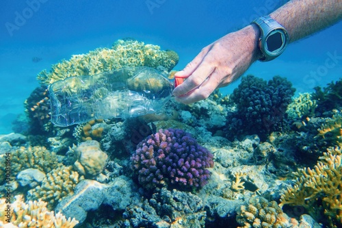 Fototapeta Naklejka Na Ścianę i Meble -  Man cleaning plastic bottle from the tropical coral reef. World ocean contaminated by  plastic. Environment pollution concept.