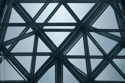 Modern architecture fragment with structural glazing. Backlit glass ceiling, roof or wall consisting of transparent panels. Abstract geometric background with polygonal pattern.