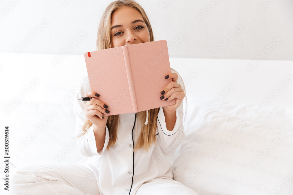 Photo of young joyful woman holding diary and looking at camera Photo of young joyful woman holding diary and looking at camera