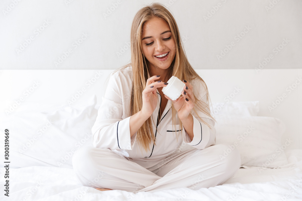 Photo of pleased caucasian woman applying cream and smiling Photo of pleased caucasian woman applying cream and smiling