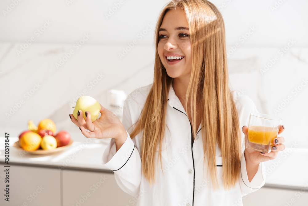 Photo of joyful pretty woman holding apple and drinking juice Photo of joyful pretty woman holding apple and drinking juice