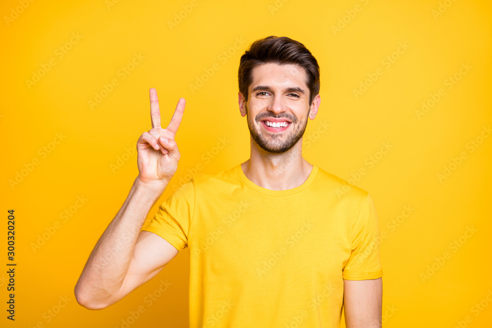 Close-up portrait of his he nice attractive funny cheerful cheery guy wearing tshirt showing v-sign good mood isolated over bright vivid shine vibrant yellow color background Close-up portrait of his he nice attractive funny cheerful cheery guy wearing tshirt showing v-sign good mood isolated over bright vivid shine vibrant yellow color background