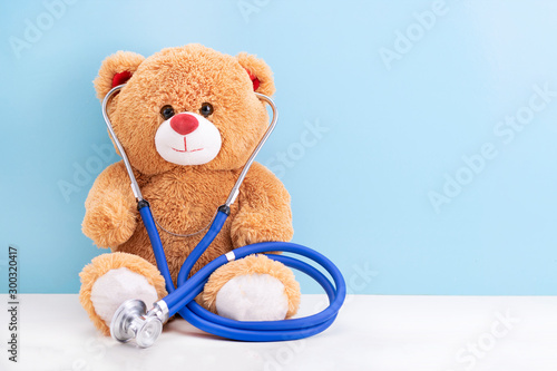 Teddy bear with stethoscope on blue background with space to copy; concept fun Pediatrics; children's medicine photo