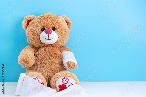 Teddy bear with bandaged hand on blue background with space to copy; concept fun Pediatrics; children's medicine