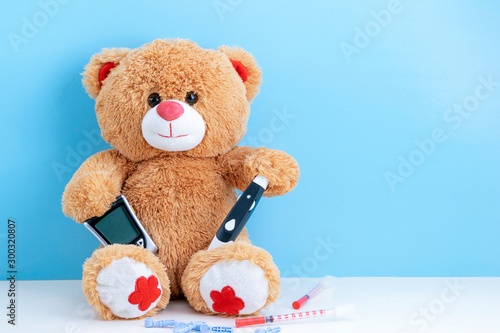 Teddy bear with blood sugar meter on blue background with space to copy; concept of diabetes in children; children's medicine; treatment of diabetes in children.