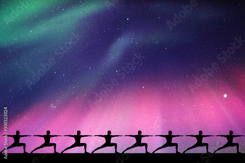 Yoga at night. Seamless vector illustration with isolated silhouettes of yogis in warrior pose. Northern lights in starry sky. Colorful aurora borealis