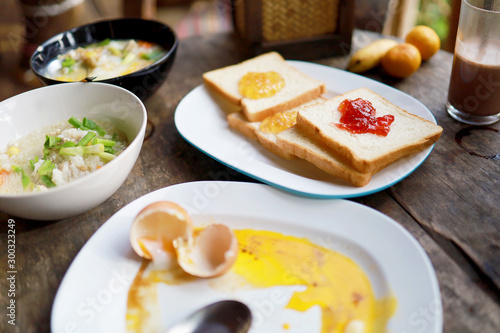 breakfast with fresh orange fruit, boiled egg, bread, orange jam, congee and coffee, selective focus.