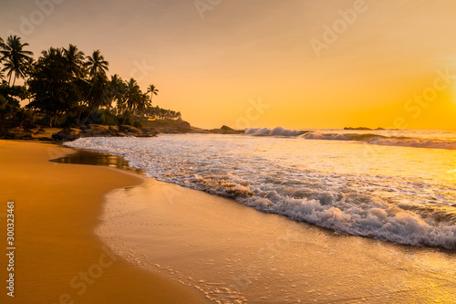 Romantic sunset on a tropical beach with palm trees