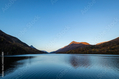 loch leven in the argyll region of the highlands of scotland during autumn showing golden light on the mountains and golden leaves on the trees © Andy Morehouse
