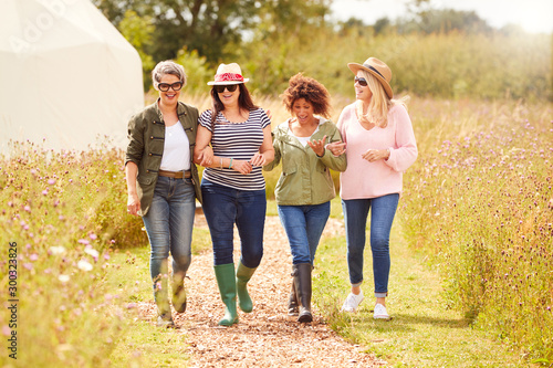 Group Of Mature Female Friends Walking Along Path Through Yurt Campsite