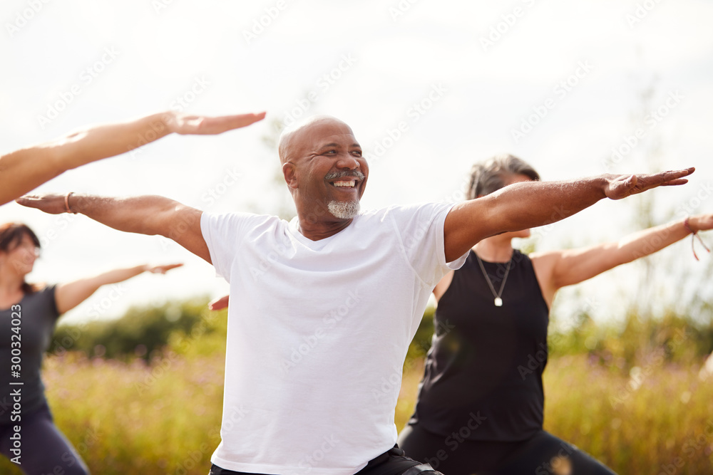 Group Of Mature Men And Women In Class At Outdoor Yoga Retreat - obrazy, fototapety, plakaty 