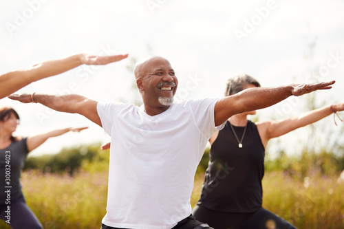 Group Of Mature Men And Women In Class At Outdoor Yoga Retreat photo