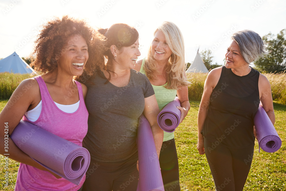 Group Of Mature Female Friends On Outdoor Yoga Retreat Walking Along Path Through Campsite - obrazy, fototapety, plakaty 