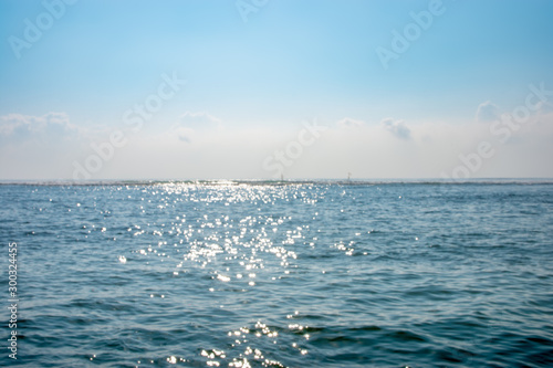 peacful calm ocean blurred background image with light sparkling off the water and horizon in the distance