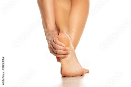 woman holding her painful heel on white background © vladimirfloyd