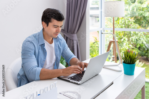 Attractive man is working at home using computer notebook
