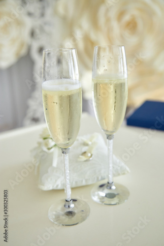Two glasses of a champagne and pillow with wedding rings..