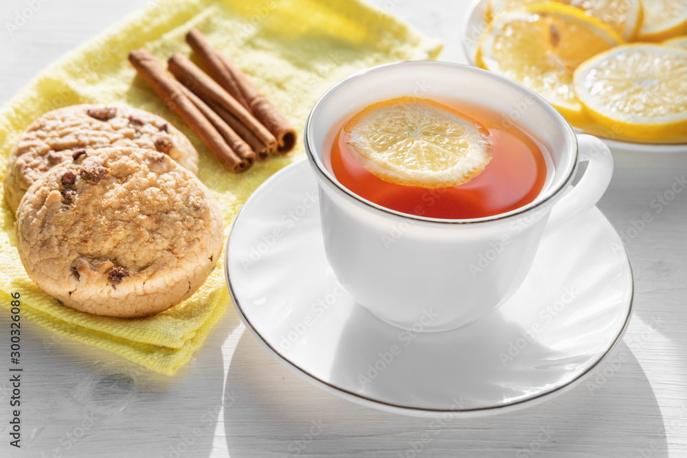White cup of tea with lemon, cookies and cinnamon. White cup of tea with lemon, cookies and cinnamon.