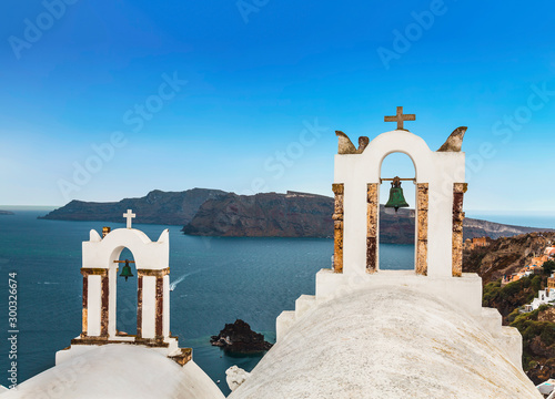 The bell towers of Greek Orthodox Church on the background waters of the Aegean sea in Oia town on Santorini island in Greece