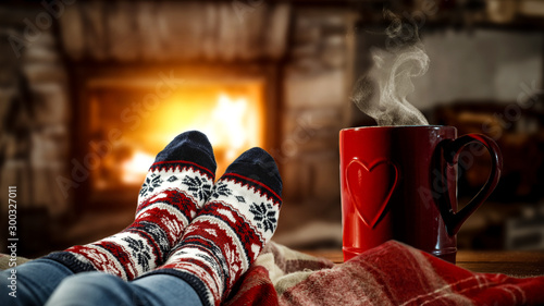 Woman legs with christmas socks and fireplace in home interior. 