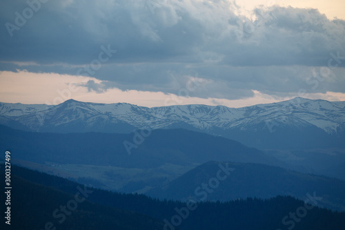 snow mountain peaks stick out on the horizon under the clouds © Andrii