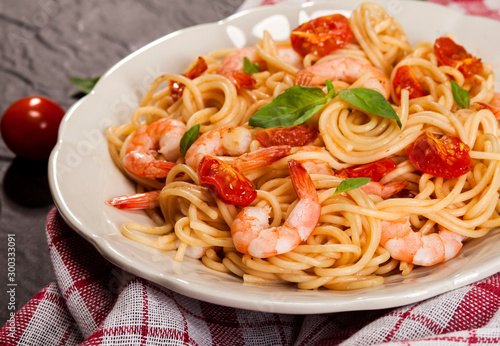 Pasta spaghetti with shrimps, dried tomato and basil on black background. Healthy meal. Italian food.