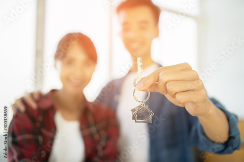 Young happy Asian couple smiling ,getting keys from new condominium real estate from agent. love buddy holding key ring to their new house or home hugging looking at camera,The joy of a new apartment
