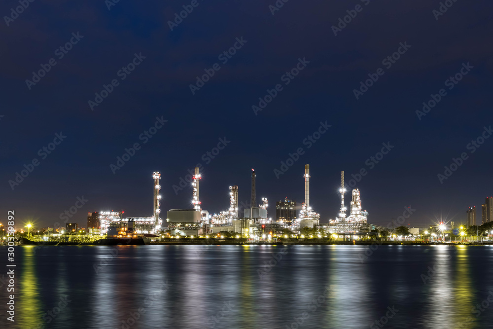 Oil refinery at night petrochemical and energy industry with refection on river